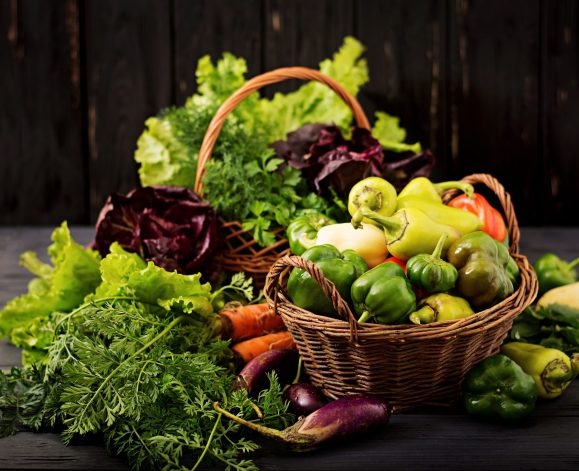 Assortment of vegetables and green herbs. Market. Vegetables in a basket on a dark background
