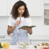 woman-writing-notebook-kitchen woman-writing-notebook-kitchen